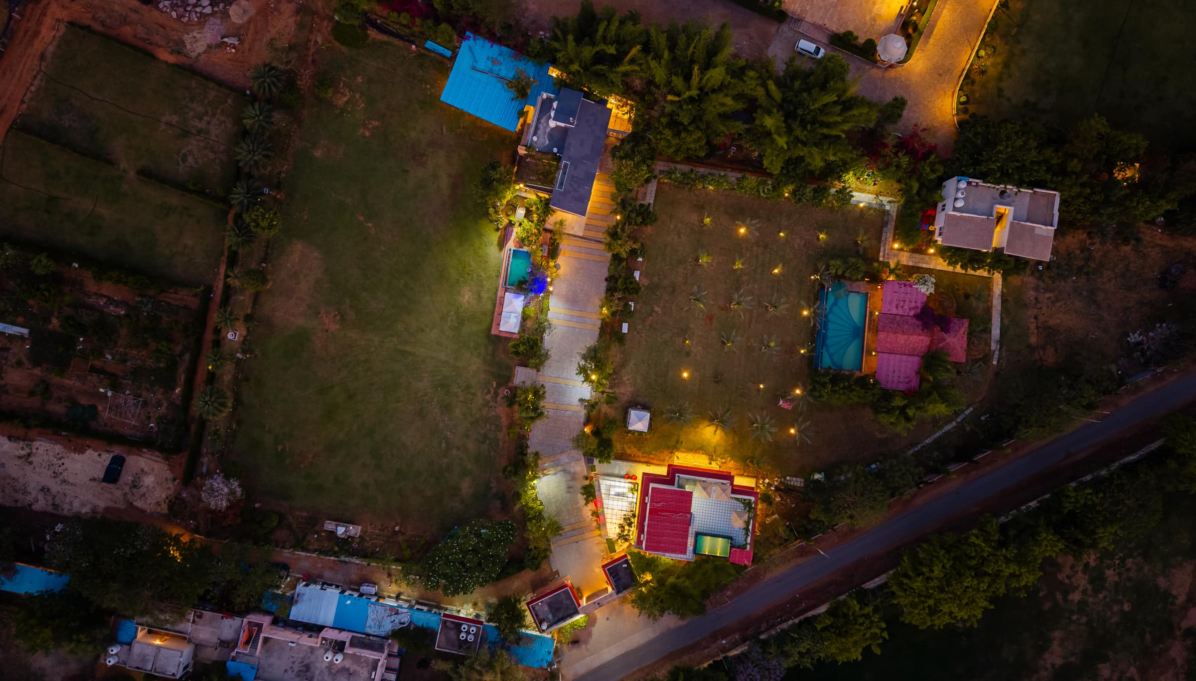 The whole farmhouse estate at dusk from the air, its paths lit by lanterns