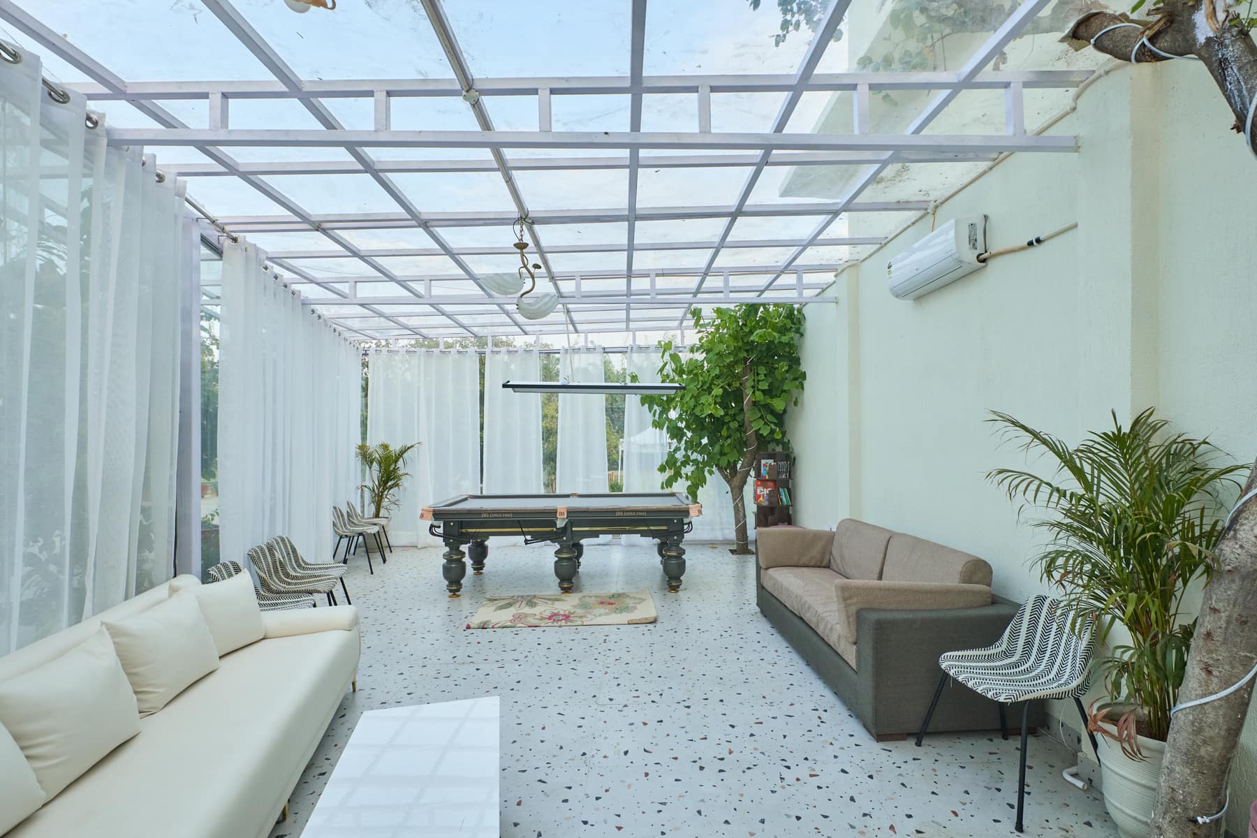 Glass-roofed games room with a billiards table and sheer curtains