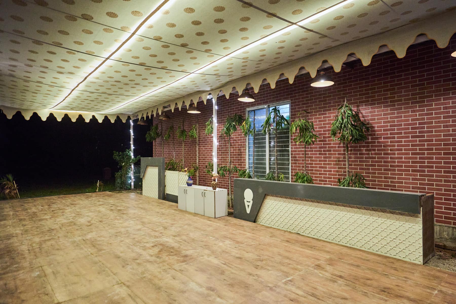 Canopied event pavilion with wooden deck against a brick wall