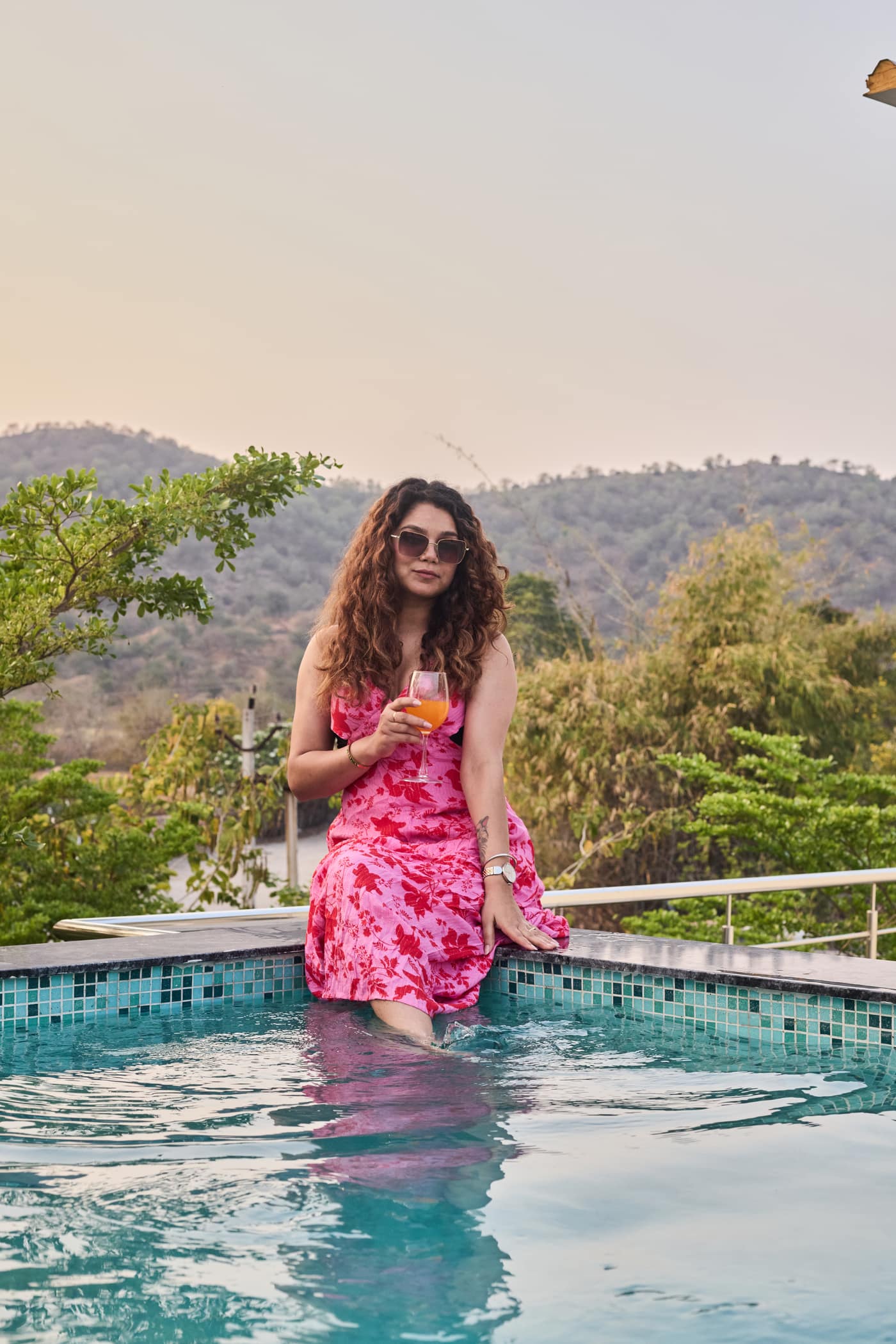 Guest sitting on the pool edge at dusk with hills in the distance