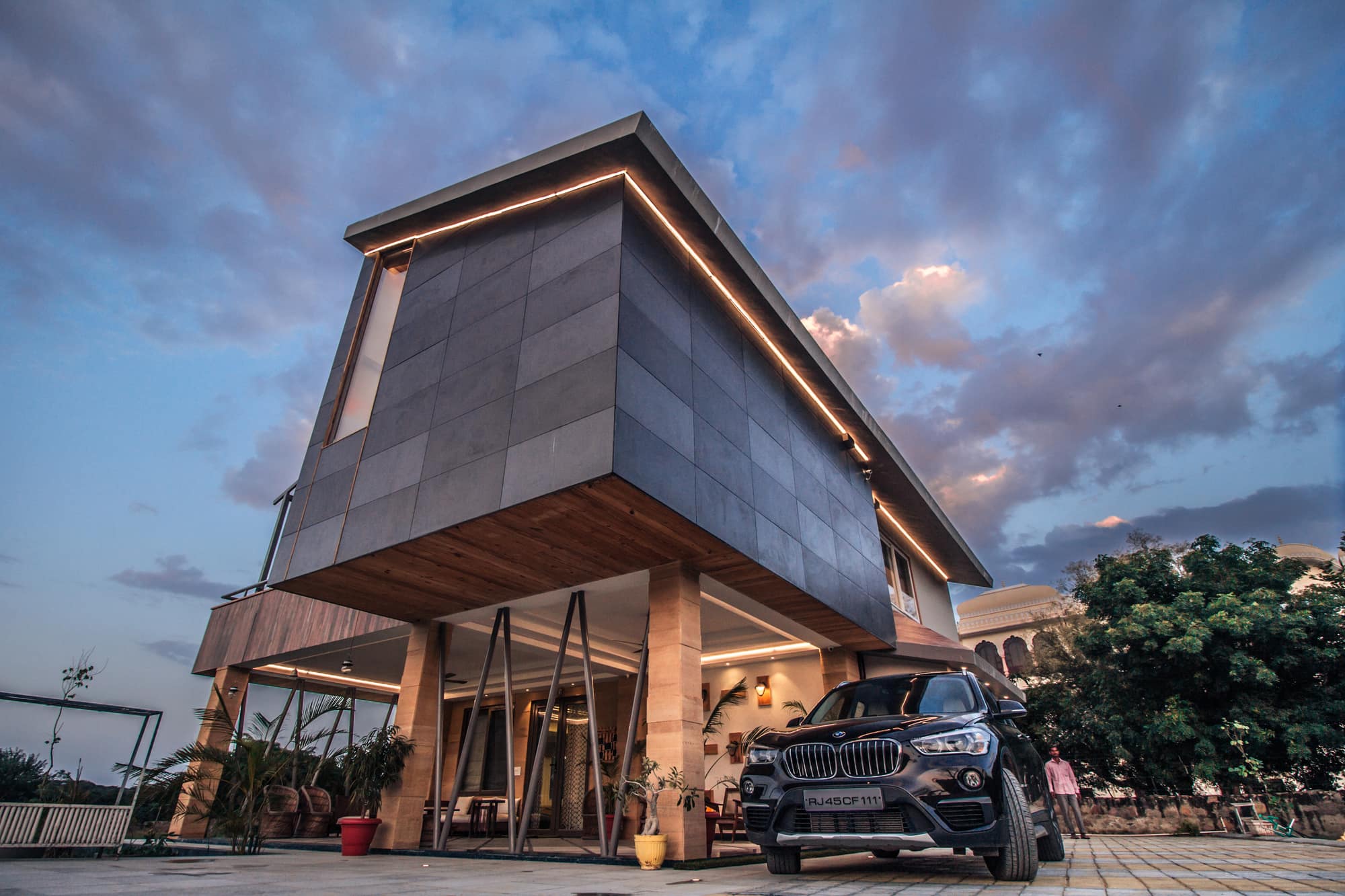 Rose Villa at dusk — a slate-clad upper floor cantilevered over a lit open porch