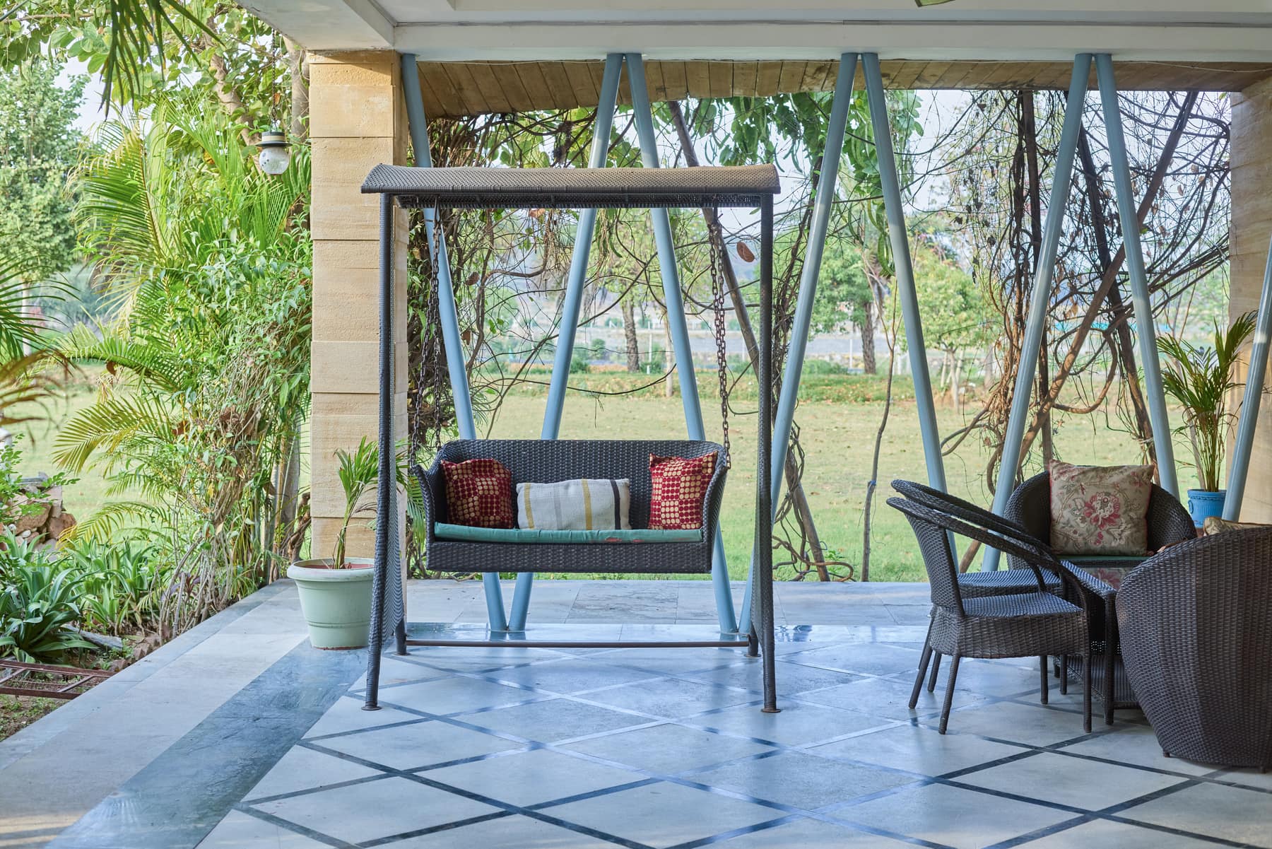 A cane swing seat on the shaded veranda, looking out over the lawns